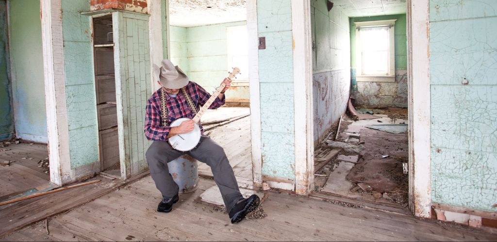 Is Banjo Hard To Learn? My Honest Opinion For Beginners A Banjo Player Playing The Banjo Inside An Abandoned House