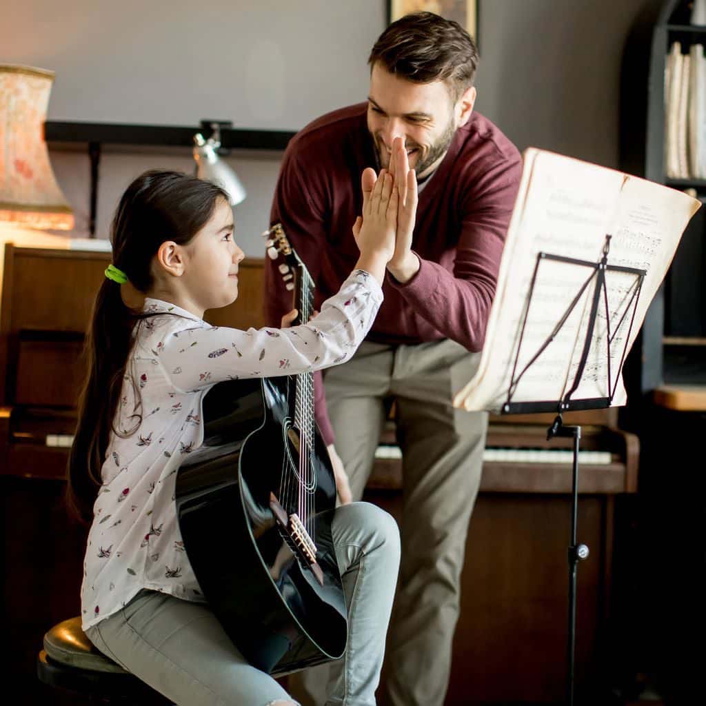 A Guitar Teacher Commending His Student For A Job Well Done Through High Five