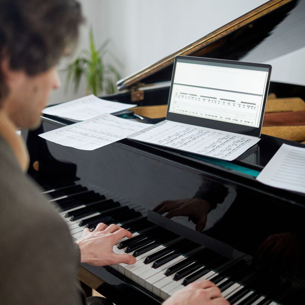 A Pianist Accessing Music Sheets Online For Playing The Piano