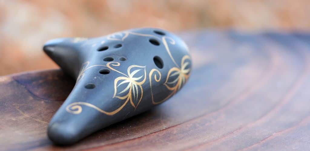 Smallest Instrument In The World A Blue Ocarina On Top Of A Wooden Surface