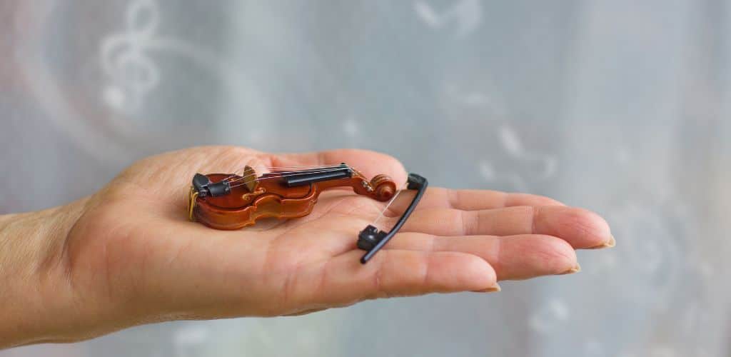 Smallest Instrument In The World A Photo Of A Small Violin On A Palm Of A Woman