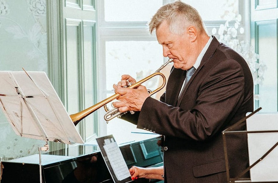 Can Playing The Trumpet Help You Live Longer? Scientists Think So! Man Playing Trumpet In Bright Hall