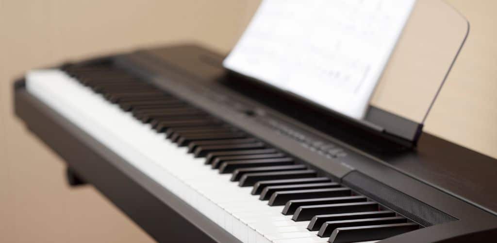Yamaha P-155: Unleashing Your Musical Potential With Ease A Digital Piano With Music Sheets On Top Of It