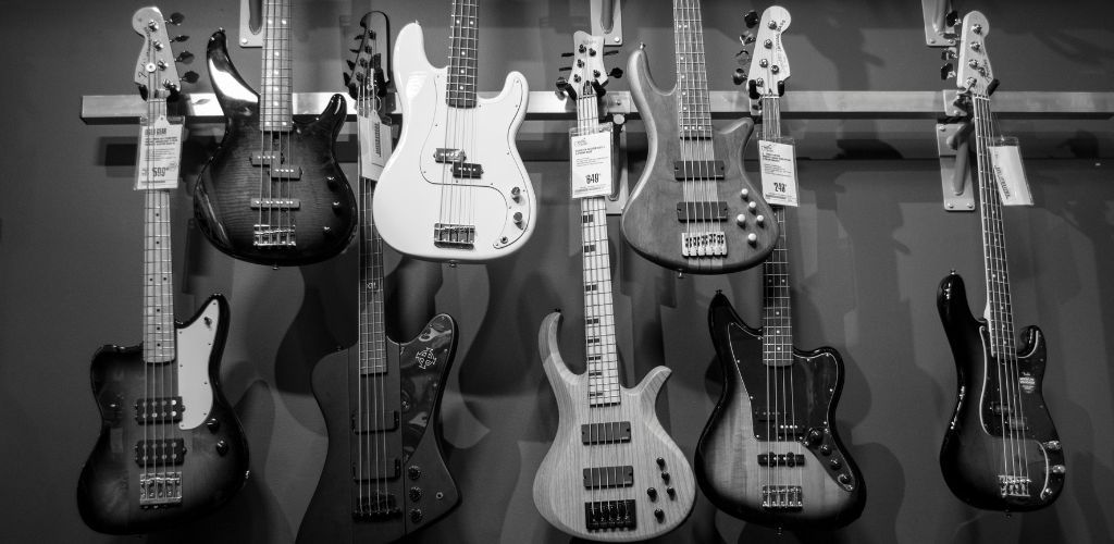 Ibanez Ergodyne Bass Guitar A Black And White Photo Of Bass Guitars Hanging On A Wall Inside A Music Store