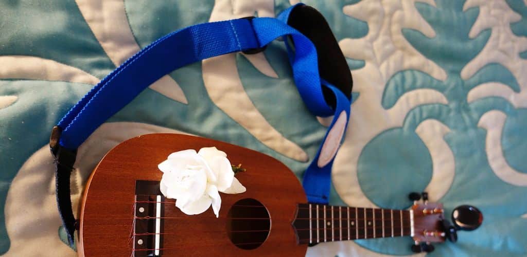 How To Put A Ukulele Strap On: Master Your Music Setup Effortlessly A Ukulele With A Blue Strap And A White Flower Resting On The Body