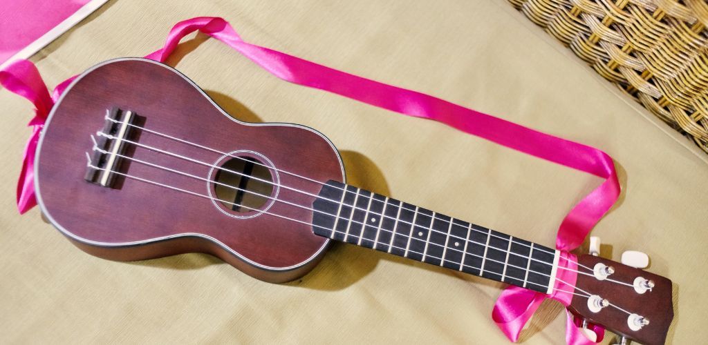 How To Put A Ukulele Strap On: Master Your Music Setup Effortlessly A Ukulele With A Pink Strap Attached To It