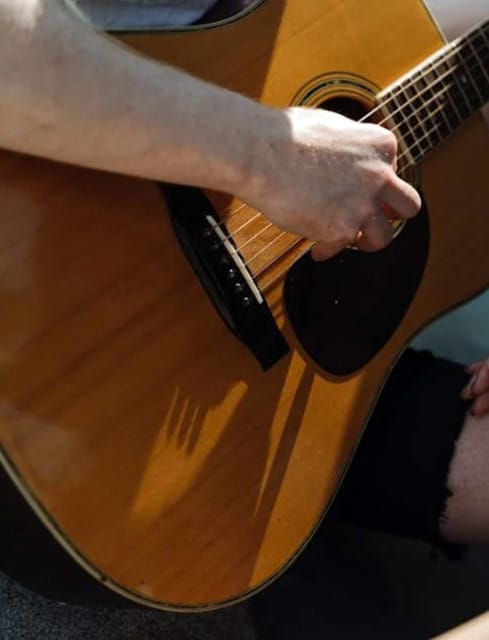 Best Acoustic Guitar For Gigging: Top Picks For Unforgettable Performances Close Up Of A Person Playing Guitar
