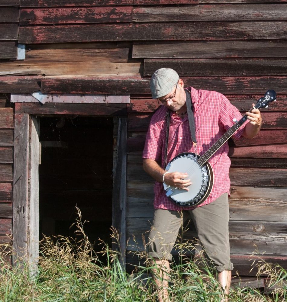 A Banjo Player Playing The Banjo Outside An Old Barn House A Banjo Player Playing The Banjo Outside An Old Barn House