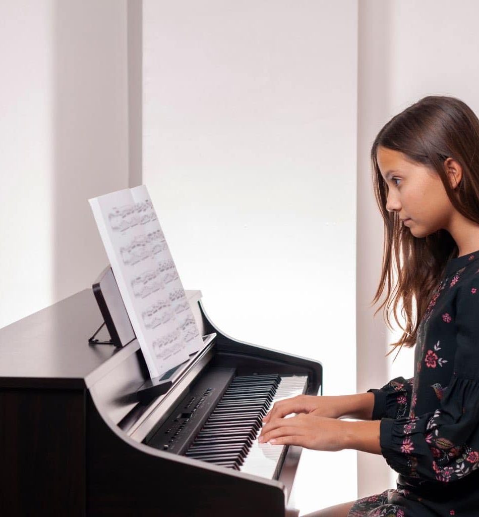 A Child Playing The Digital Piano While Using The Music Rest