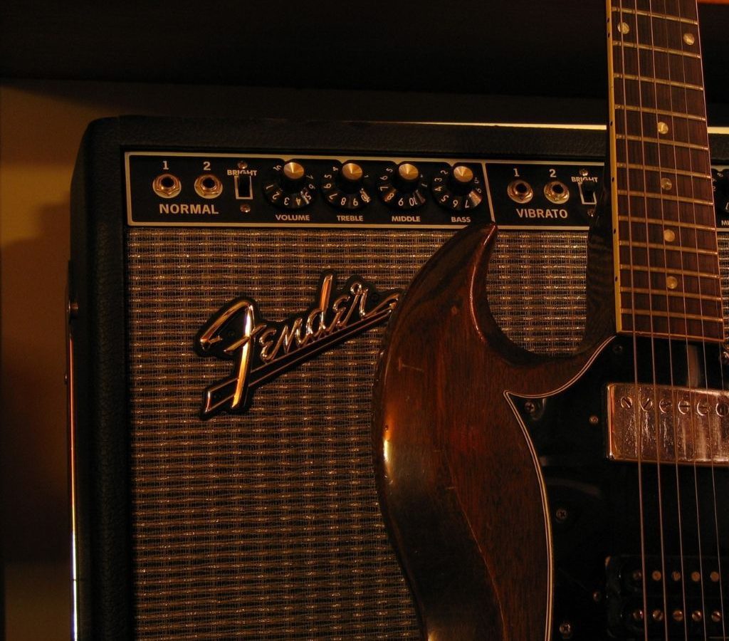 A Fender Amplifier With A Guitar Resting On It