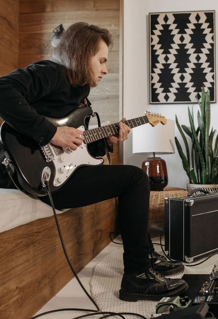 A Guitarist Playing A Black Electric Guitar With Guitar Effects And Portable Guitar Amplifier A Guitarist Playing A Black Electric Guitar With Guitar Effects And Portable Guitar Amplifier