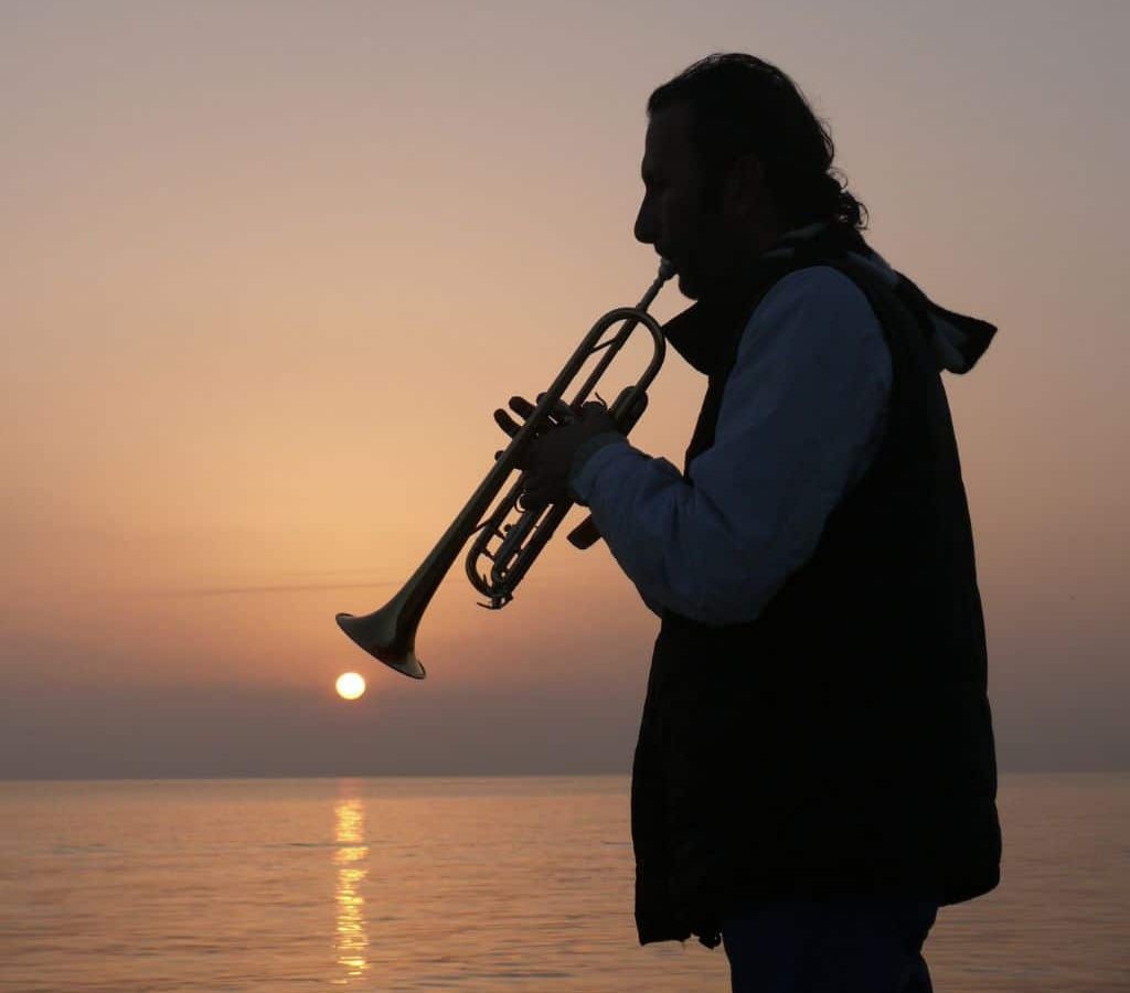 A Trumpet Player Playing The Trumpet By The Sea During Sunset A Trumpet Player Playing The Trumpet By The Sea During Sunset