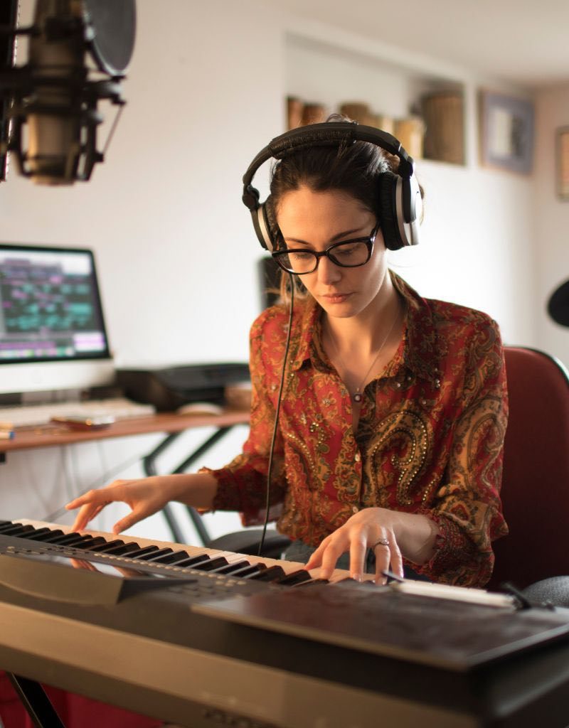 A Woman Recording And Editing Music Through A Piano Keyboard A Woman Recording And Editing Music Through A Piano Keyboard