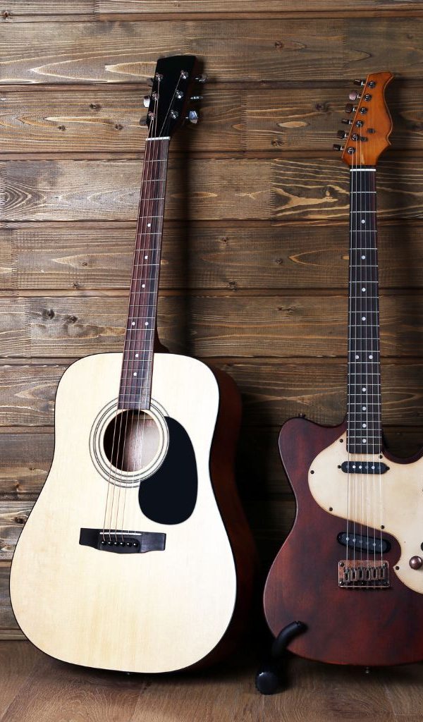 An Intermediate Acoustic And Electric Guitar Leaning On A Wooden Wall An Intermediate Acoustic And Electric Guitar Leaning On A Wooden Wall