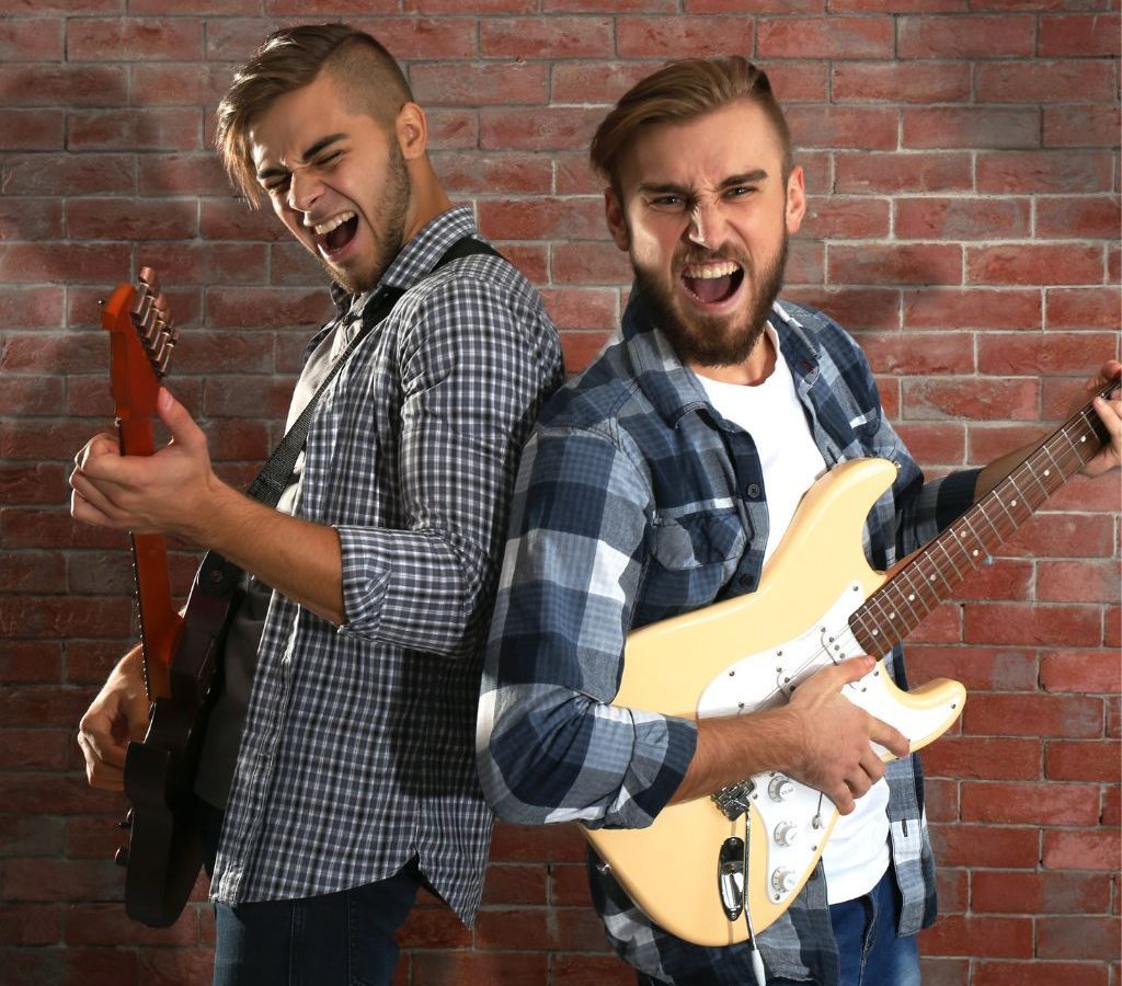 Two Electric Guitarist Joyfully Playing Back To Back By A Brick Wall Two Electric Guitarist Joyfully Playing Back To Back By A Brick Wall